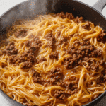 Close-up of creamy garlic butter pasta with ground beef in a nonstick pan