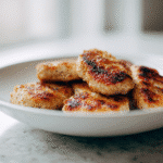 Flat lay of grilled keto chicken nuggets and ingredients on white kitchen counter
