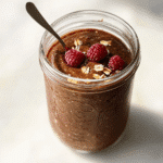 Chocolate raspberry overnight oats in a clear mason jar, ready to eat