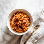 overhead of spaghetti and meat sauce in white bowl
